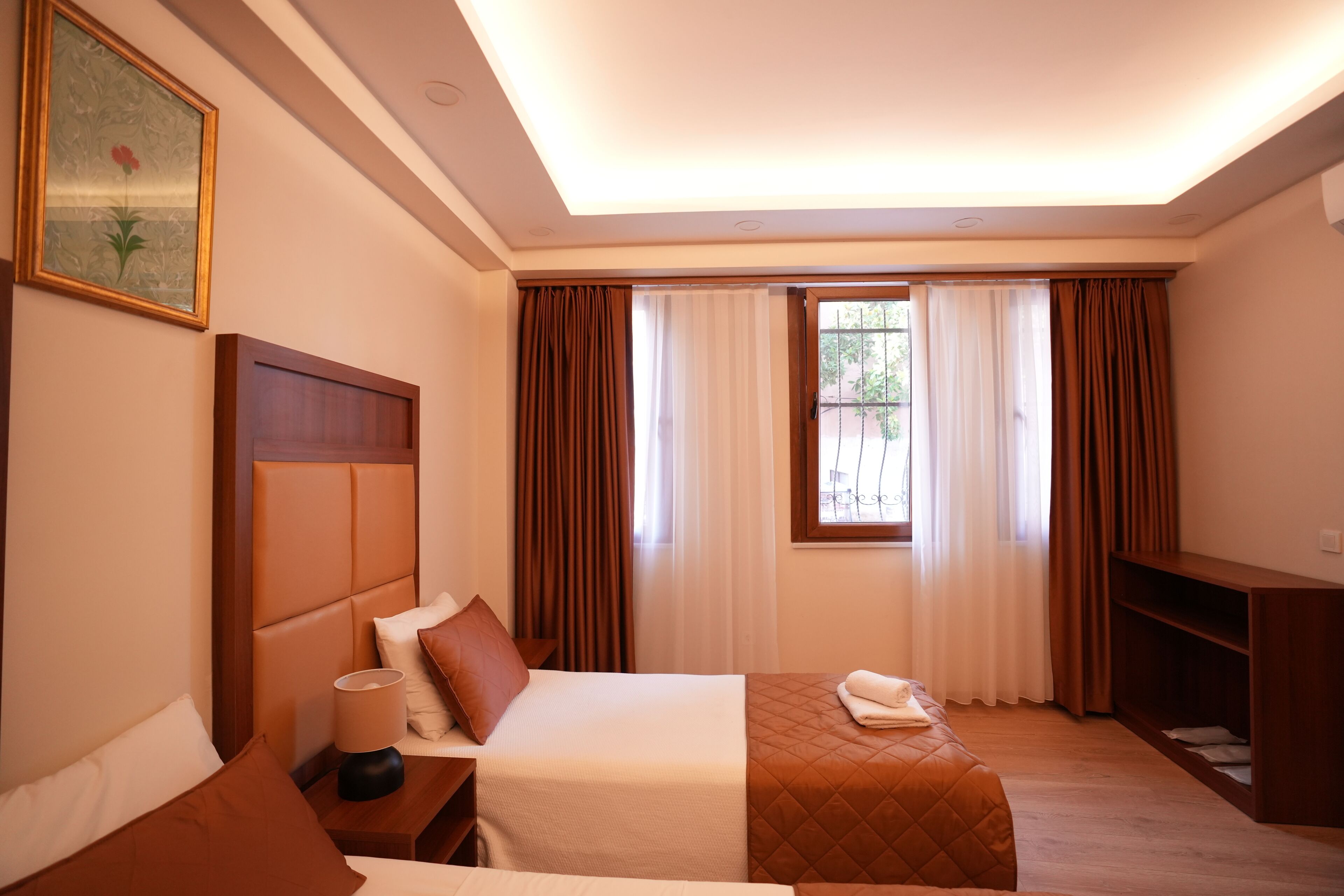 A hotel room with a bed, bedside table, lamp, and a TV stand.