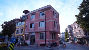 En lyserød bygning med skiltning for en restaurant og et apotek.