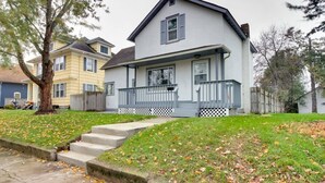 A two-story house with a front porch, a small front yard, and a tree in the foreground.