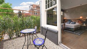 Un balcon avec une table et des chaises, un lit avec des oreillers et une vue sur la ville.