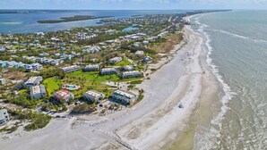 An aerial view of a coastal residential area with houses, a beach, and a marina. - Gulf Views & Cozy Comfort w Large Lanai Tern's Nest #22 Condo by RVA (Longboat Key)