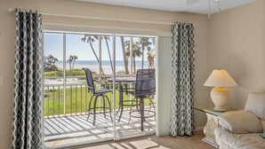 A room with a balcony, a table with chairs, a lamp, and a sofa. - Gulf Views & Cozy Comfort w Large Lanai Tern's Nest #22 Condo by RVA (Longboat Key)