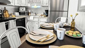 A modern kitchen with white cabinets, stainless steel appliances, and a neon sign. - Cozy PC Condo | Top Floor Studio (Park City)