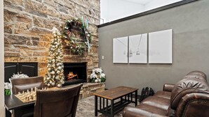 A cozy living area with a stone fireplace, a Christmas tree, and a leather sofa. - Cozy PC Condo | Top Floor Studio (Park City)