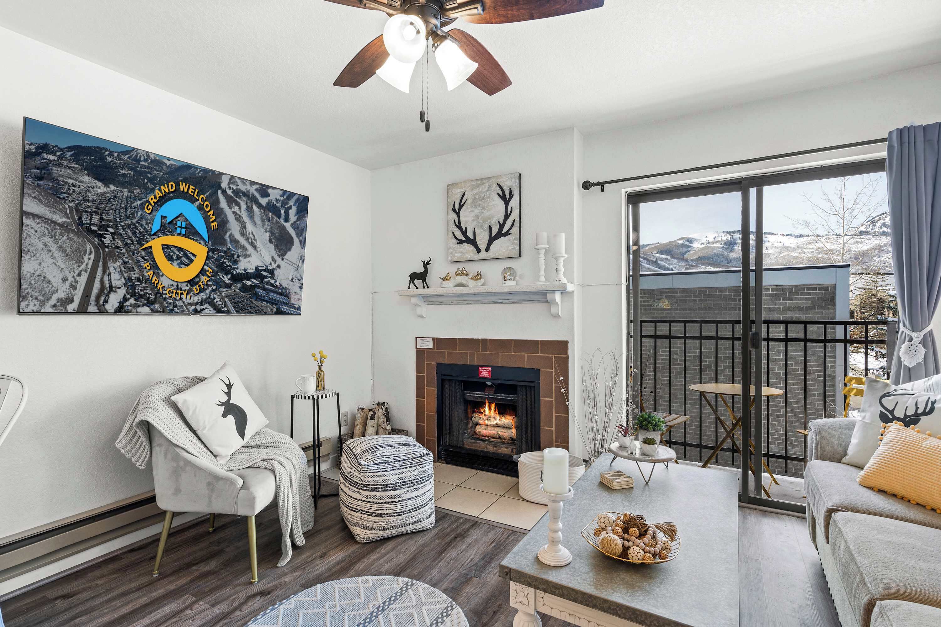 A living room with a fireplace, a large window, and a view of the mountains.