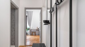 A hallway with a wooden floor, a black bench, and a desk with a chair. - Apartment del Bello (Koper)