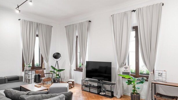 A modern living room with a sofa, TV, and potted plants. - Apartment del Bello (Koper)