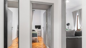A modern interior with a wooden herringbone floor, a grey sofa, and a desk with a computer. - Apartment del Bello (Koper)