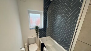 Un baño con inodoro blanco, bañera y zona de ducha.