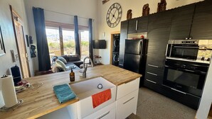 Een kleine keuken met een houten aanrecht, een spoelbak, een koelkast en een oven.