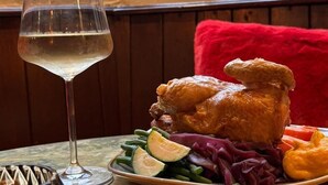 Una mesa con un plato de comida, una copa de vino blanco y una vela.