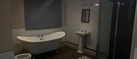 Une salle de bain avec une baignoire sur pieds, un lavabo sur colonne, des toilettes et une douche à parois de verre.