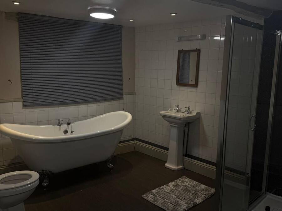 A bathroom with a freestanding bathtub, a pedestal sink, a toilet, and a glass-enclosed shower.