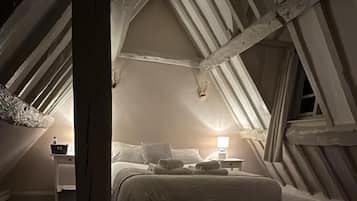 A cozy attic bedroom with a bed, two bedside tables, and a hanging light fixture.