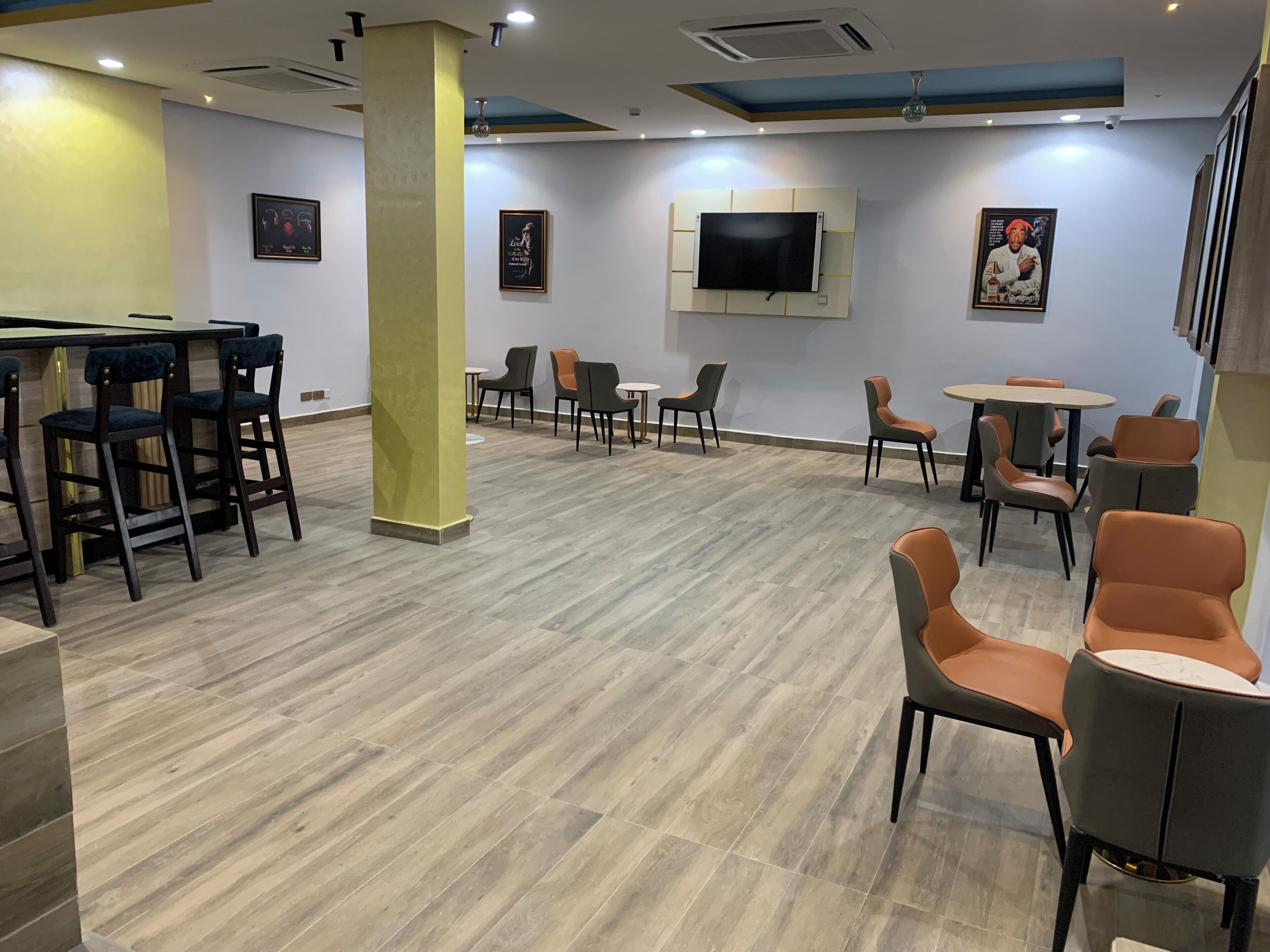 A modern interior with a bar area, multiple seating options, and a mounted TV.