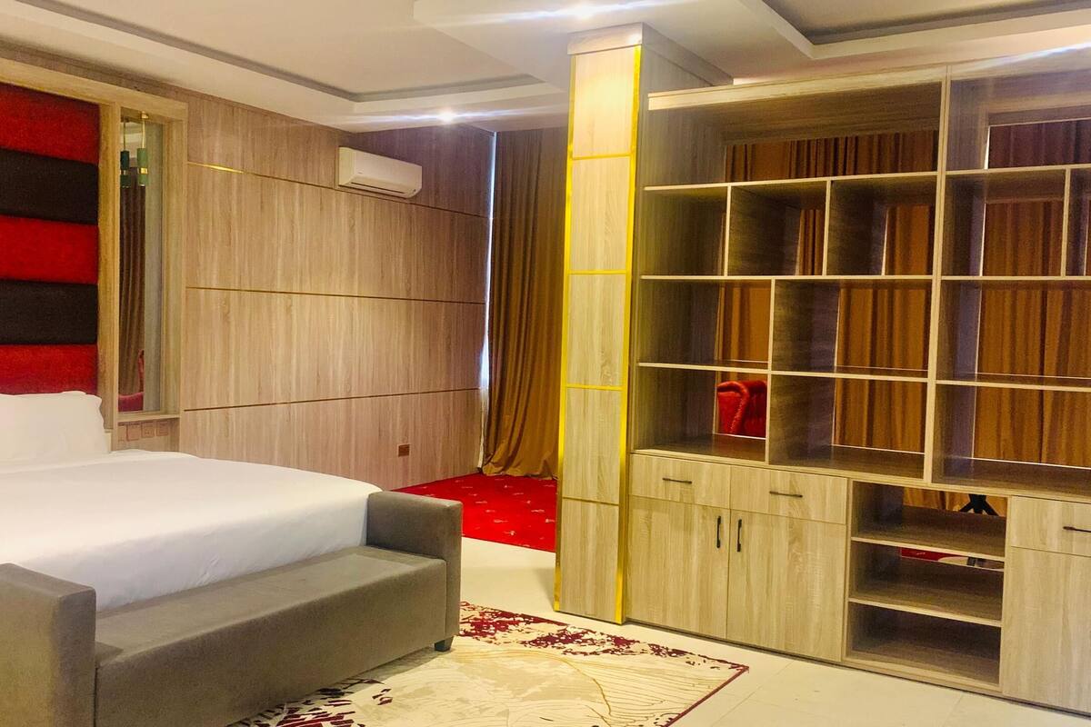 Ein modernes Schlafzimmer mit einem großen Bett, integriertem Kleiderschrank und einer roten Akzentwand.