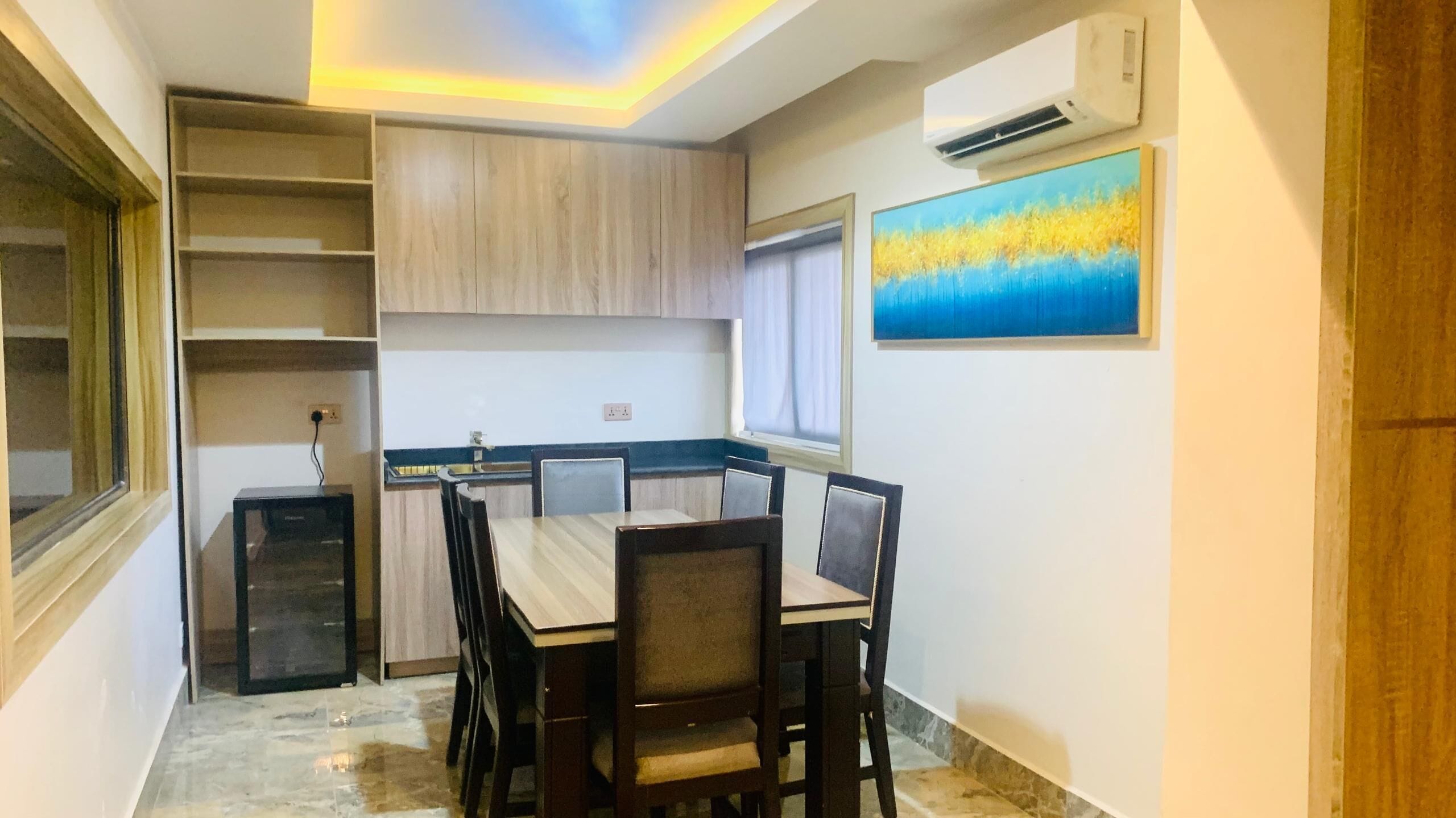 A compact kitchen with built-in cabinets, a dining table with chairs, and a window with curtains.