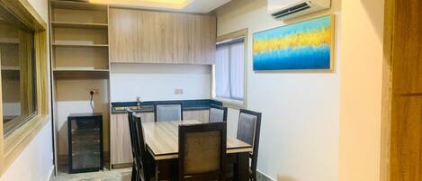 A compact kitchen with built-in cabinets, a dining table with chairs, and a window with curtains.
