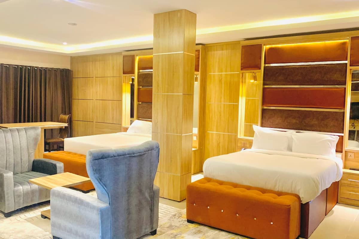 Ein modernes Hotelzimmer mit einem großen Bett, zwei Sesseln, einem kleinen Tisch und einem Einbauschrank.