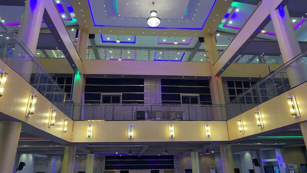 A multi-level atrium with a modern design, featuring a central chandelier, glass railings, and multiple light fixtures. - Ceedapeg Hotels (Uyo)