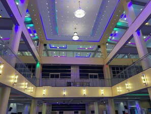 A multi-level atrium with a modern design, featuring a central chandelier, glass railings, and multiple light fixtures. - Ceedapeg Hotels (Uyo)