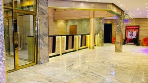 A hotel lobby with marble flooring, a reception desk with illuminated panels, and a poster promoting unity. - Ceedapeg Hotels (Uyo)
