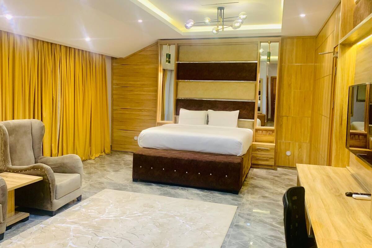 Ein Hotelzimmer mit Bett, Sofa, Schreibtisch und Fernseher.