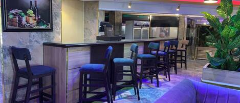Un'area bar con un bancone, sgabelli da bar e un divano.