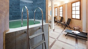 A spa area with a hot tub, a ladder, lounge chairs, and a tiled floor. - Wellness hotel Jean de Carro (Karlovy Vary)