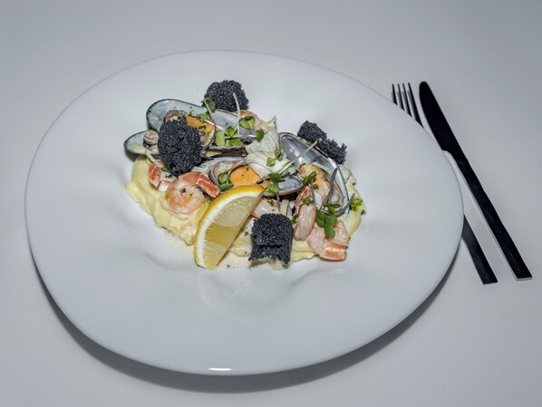 A plate of seafood pasta with lemon and greens.