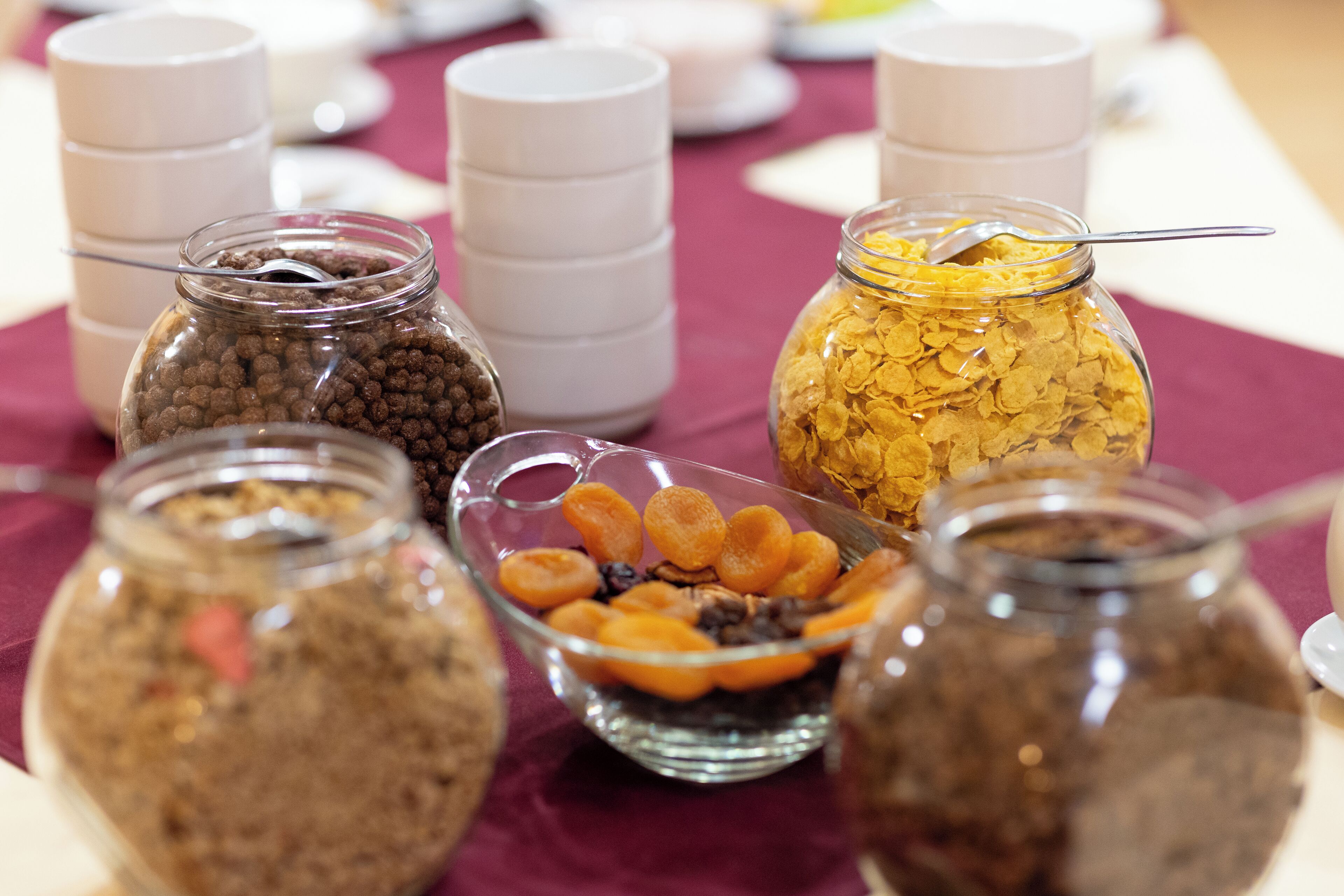 A table with various food items in jars and bowls, including cereal and dried fruits.