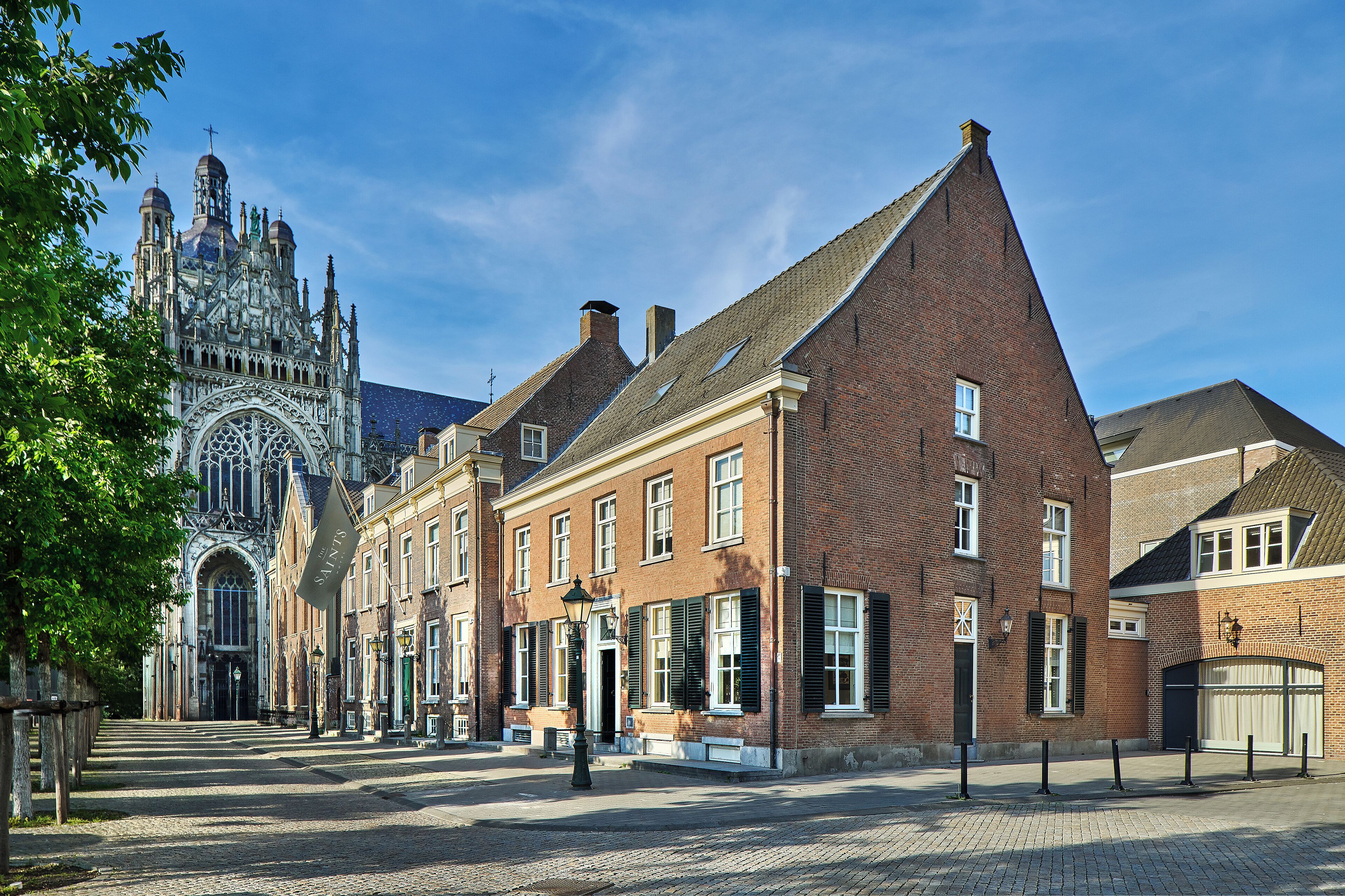 Une rue historique bordée de bâtiments traditionnels en briques, une église imposante à l’architecture complexe et un pavé de pierres.