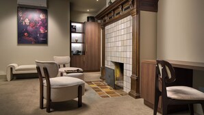 A cozy room with a fireplace, a large painting, and a seating area with chairs and a sofa. - The Saints Hotel ('s-Hertogenbosch)