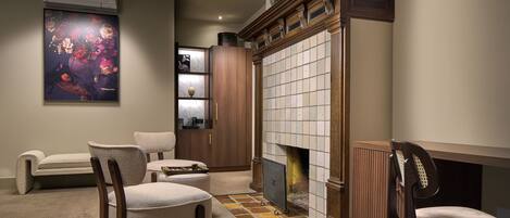 A cozy room with a fireplace, a large painting, and a seating area with chairs and a sofa.
