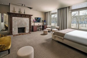 Habitación de hotel con chimenea, una cama grande, escritorio y vistas al exterior.