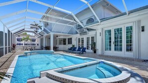 Ein überdachter Pool mit Whirlpool, Liegestühlen und einer Terrasse mit Esstisch.
