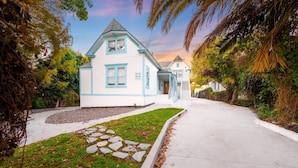 A two-story house with a gabled roof and a front porch, surrounded by lush greenery and a stone pathway leading to the entrance. - 25% Off Sept 24-27 Amazing Reviews, Walk To Beach* (Ventura)