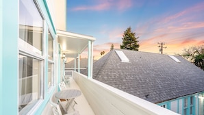 A balcony with a table and chairs, a covered area with a railing, and a view of a neighboring house with a sloped roof. - 25% Off Sept 24-27 Amazing Reviews, Walk To Beach* (Ventura)