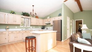 A kitchen with wooden cabinets, a central island, and a refrigerator. - Boats N Oats: Great family getaway, wifi, gentle lot, kayak (Moneta)