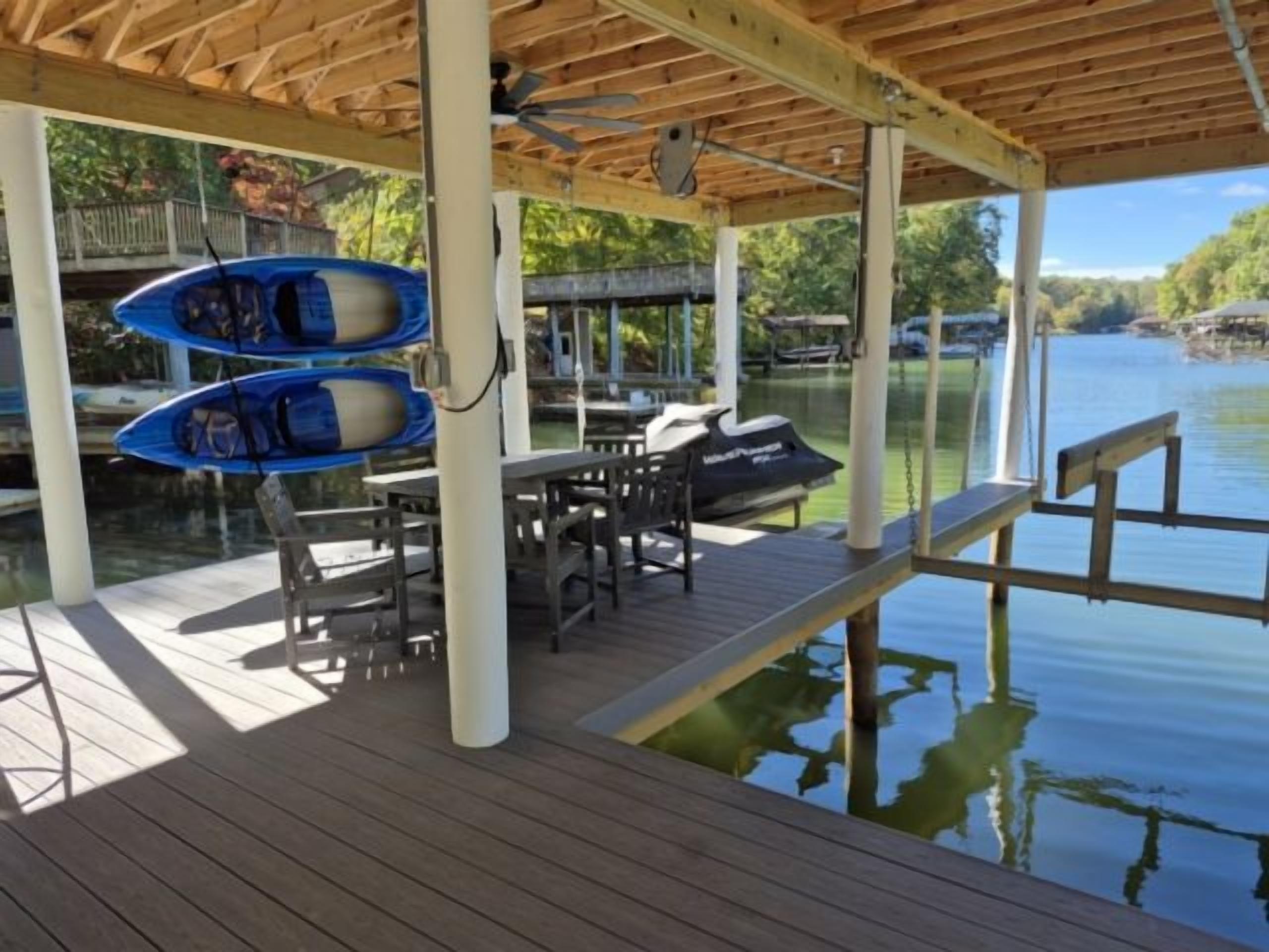 Een houten terras met een tafel, stoelen, een boot en een jetski.