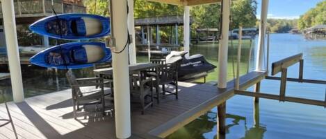 A wooden deck with a table and chairs, a boat, and a jet ski.