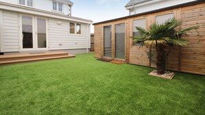 Patio trasero residencial con césped cuidado, cerca de madera y una palmera.