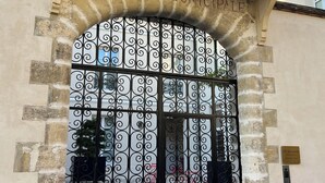 Ein verschlossenes Tor mit einem Schild, auf dem 'MAISON MUNICIPAL' steht, über einem verzierten Metallgitter.