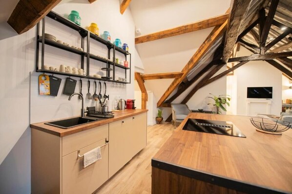 Una cocina moderna con vigas de madera, un estante empotrado con utensilios de cocina y una isla central.