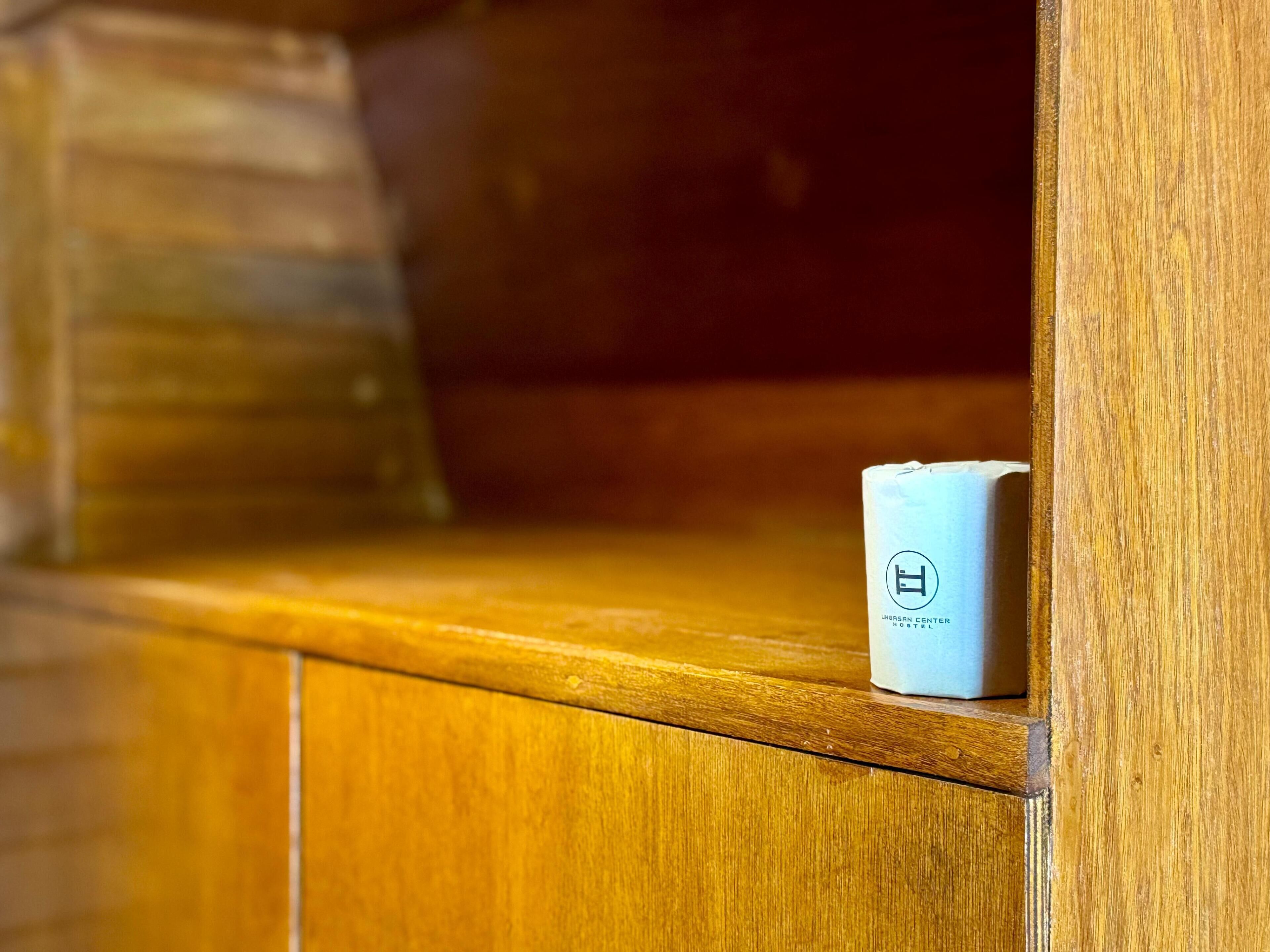 Un objeto blanco pequeño con un logotipo sobre una superficie de madera, posiblemente un control remoto o dispositivo.