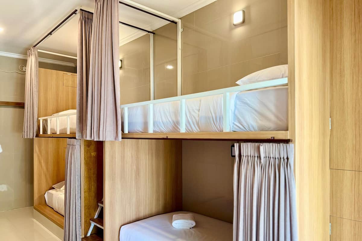 Une chambre avec un lit superposé, un lit simple et une armoire en bois.
