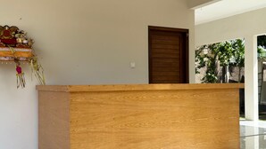 Un mostrador de recepción de madera en un moderno vestíbulo, con una pared lisa y una puerta a la derecha.