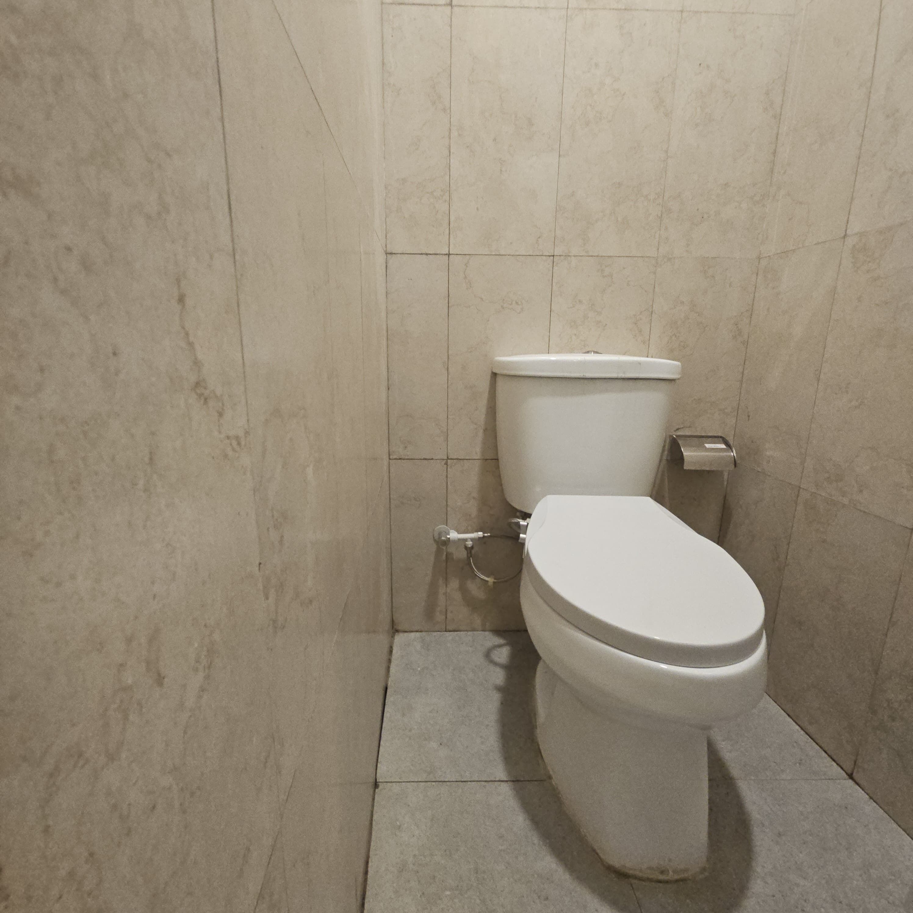 A bathroom with a toilet, a bidet, and tiled walls.