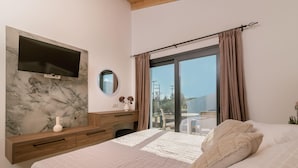 Ein Schlafzimmer mit einem Bett, einem an einer Marmorwand montierten Fernseher, einem Schminktisch und einem Fenster mit Vorhängen.