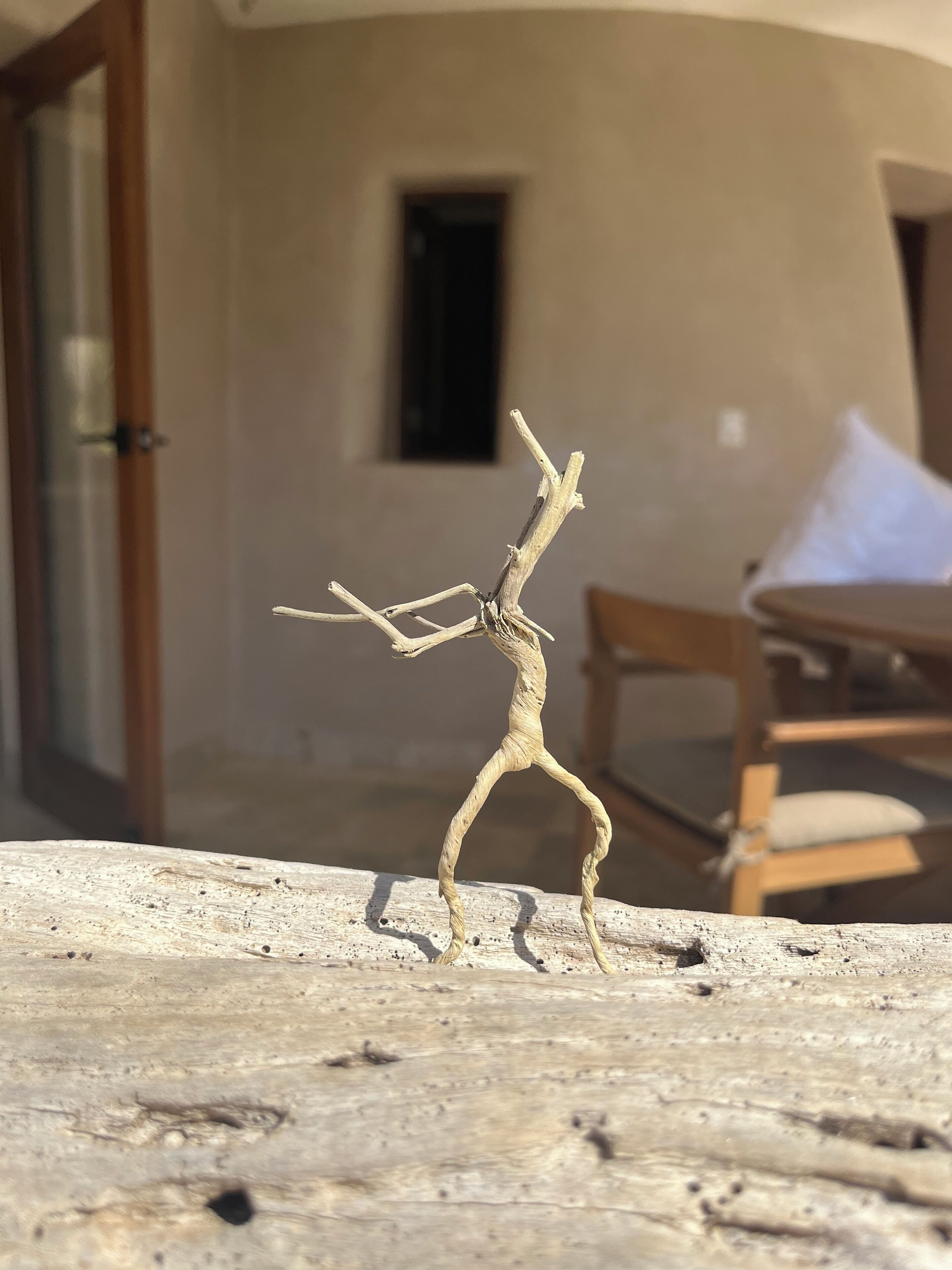 A wooden sculpture of a dancing figure outdoors.